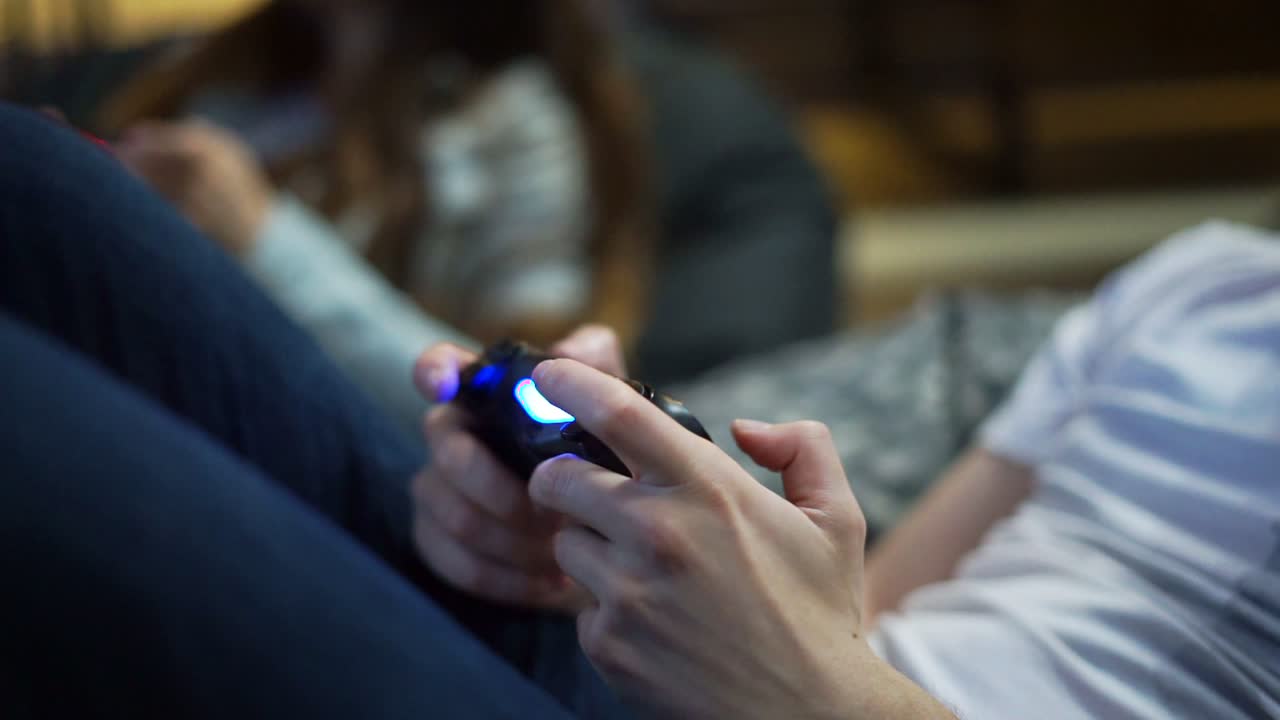 Close Up view of man's hands playing video game at home. Shooting and controlling using the game controller. Wireless game