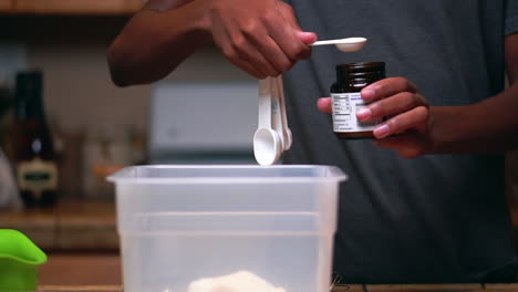 measuring yeast with a teaspoon to add to flour to make batter or dough