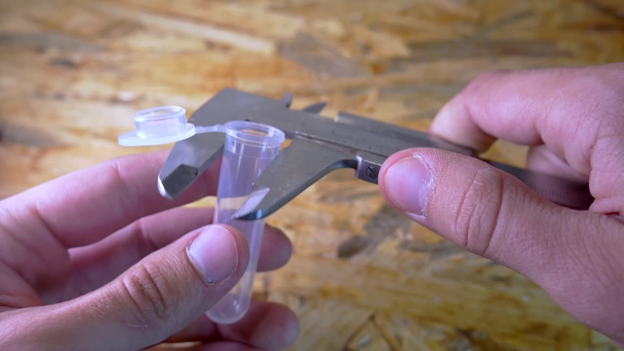 tubo de ensayo de plástico de medición con calibre en el taller solo manos 4k