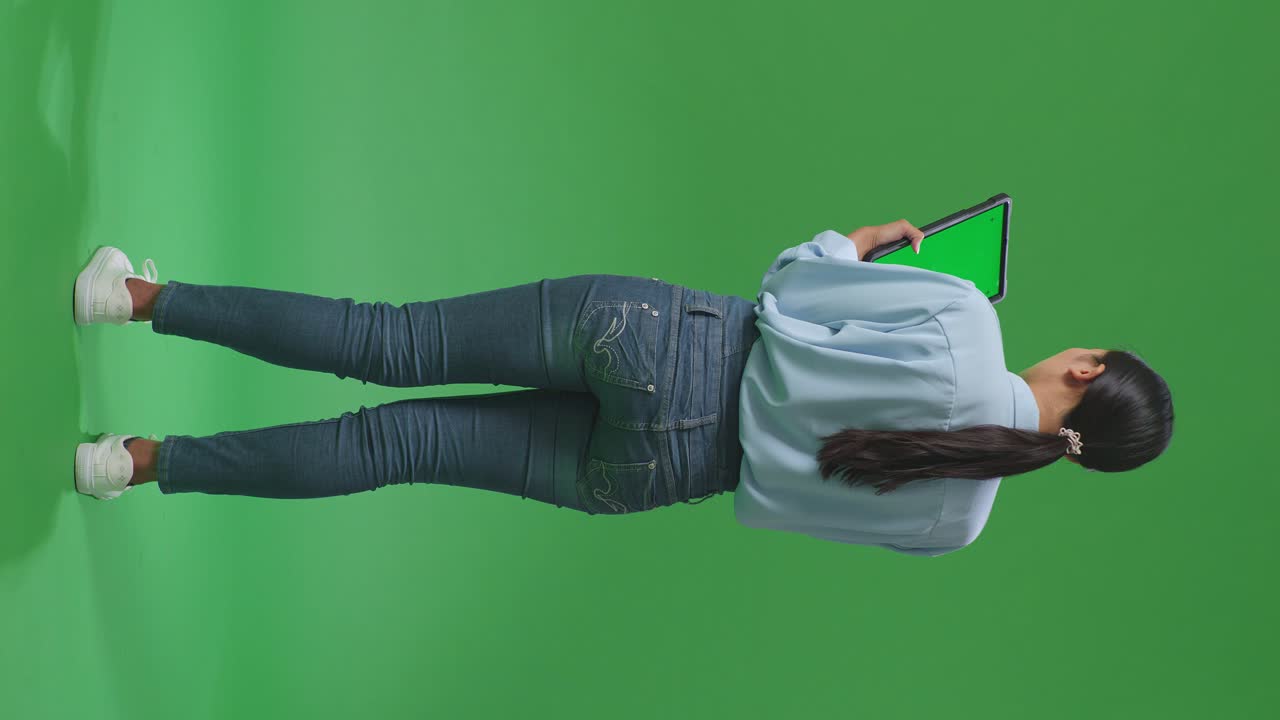 vista trasera de cuerpo completo mujer de negocios asiática usando tableta con pantalla verde simulada en fondo de pantalla verde en el estudio