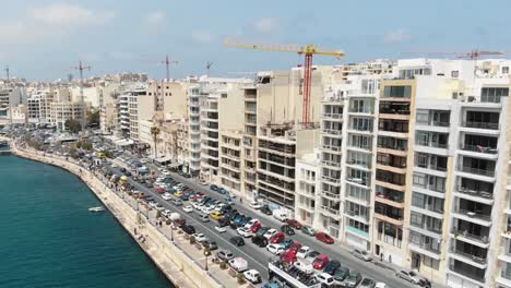 aerial 4k drone footage flying towards a heavy trafficked area of a coastal city block of sliema, a densely populated mediterranean community on the island of malta