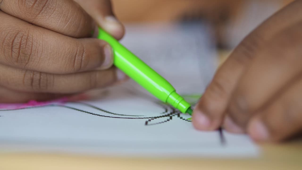 Child coloring with a green marker