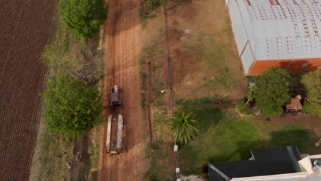 Aerial,-water-tank-pulled-by-old-tractor-in-town-street-in-Argentina