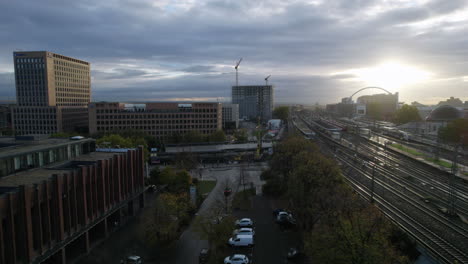 Sun-shining-through-dark-clouds-over-the-modern-buildings-in-the-city-Köln-next-to-a-train-station