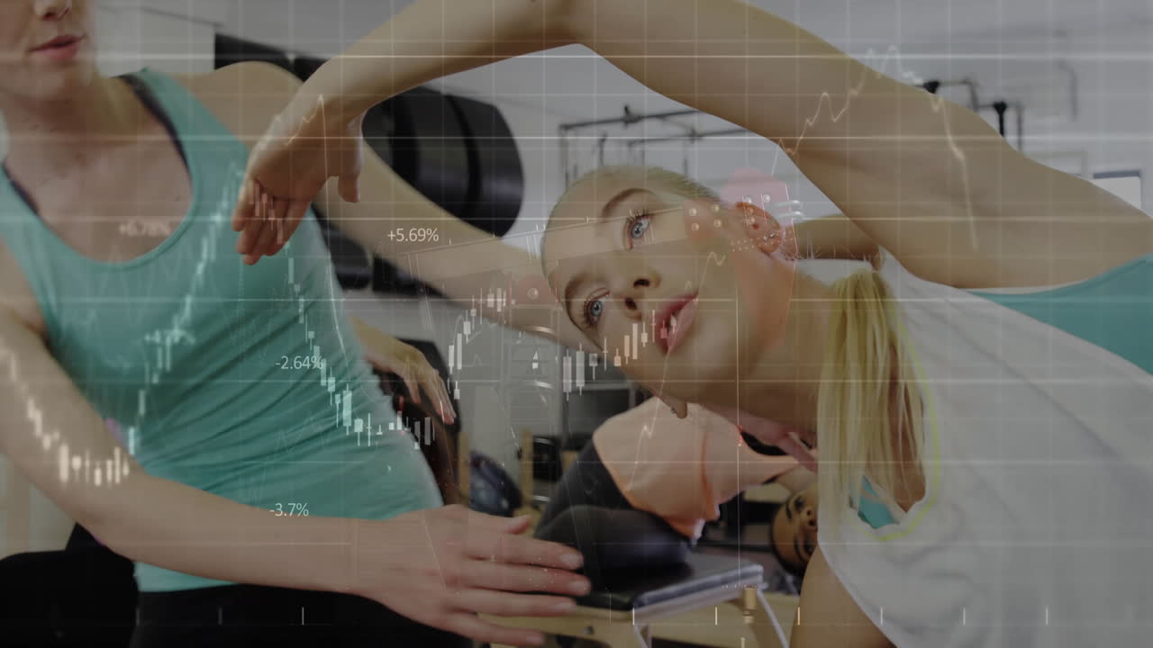 Women stretching in gym with stock market data animation overlay