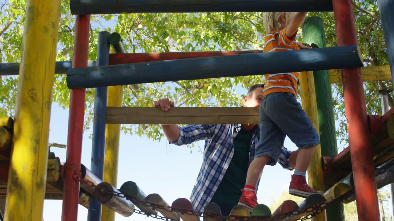 Boy climbing an small wooden hanging bridge on the playground 4k