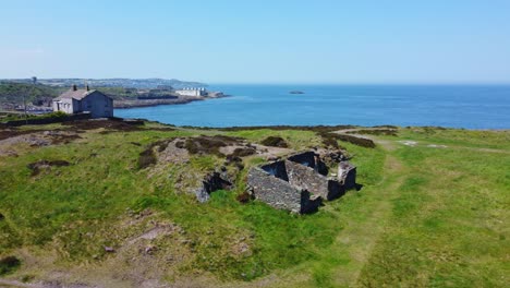 Abandoned-Amlwch-coastal-countryside-mountain-house-aerial-slow-low-rising-view-overlooking-Anglesey-harbour