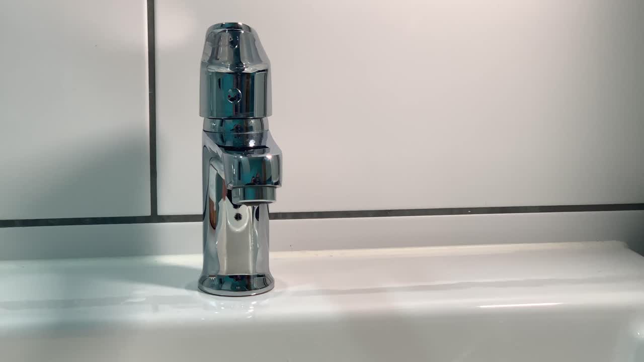 cámara lenta de gotas de agua que se escapan del grifo del baño