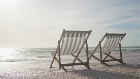 two empty deckchairs standing on beach at sunset
