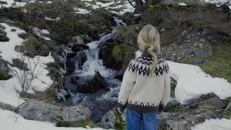 child watching a mountain waterfall in winter