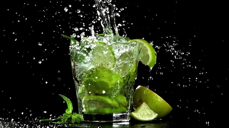 Versamento di acqua al rallentatore in un bicchiere da Mojito con lime e menta