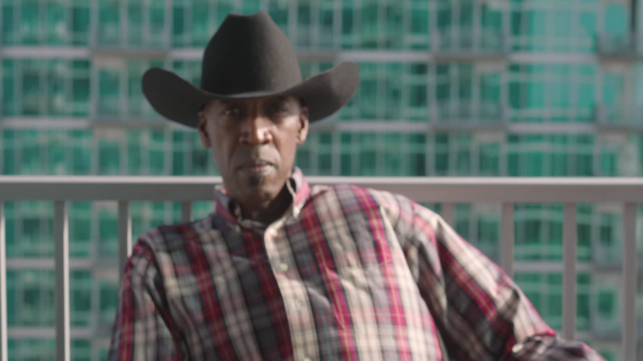 en el tiro de un hombre negro con sombrero de vaquero negro sonriendo