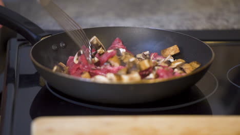 pilze und steak in zeitlupe in einer pfanne kochen