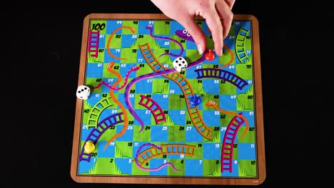 hand moving pieces on snakes and ladders board