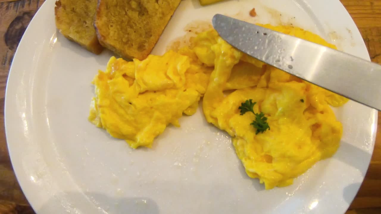 timelapse aéreo de huevos revueltos, salchicha de cerdo, pan de plátano y desayuno de piña que se come