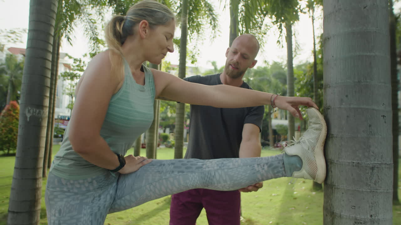 Woman Doing Stretch in Park with Personal Trainer