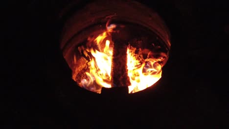 slow motion burning wood logs on fire in a barrel at night