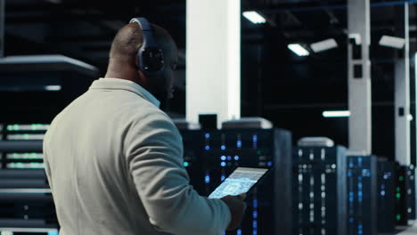 vertical video admin walking in data center, listening music while doing inspection