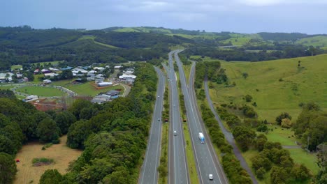 Vehículos-Que-Conducen-En-La-Autopista-Del-Pacífico-Por-Exuberantes-Colinas-Y-Campos-Desde-Byron-Bay-Hasta-Brisbane-En-Queensland,-Australia