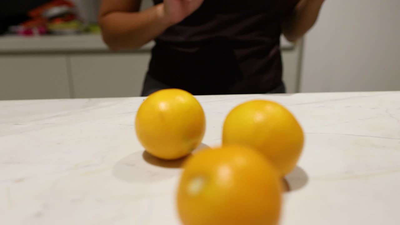 Oranges being moved on a kitchen countertop