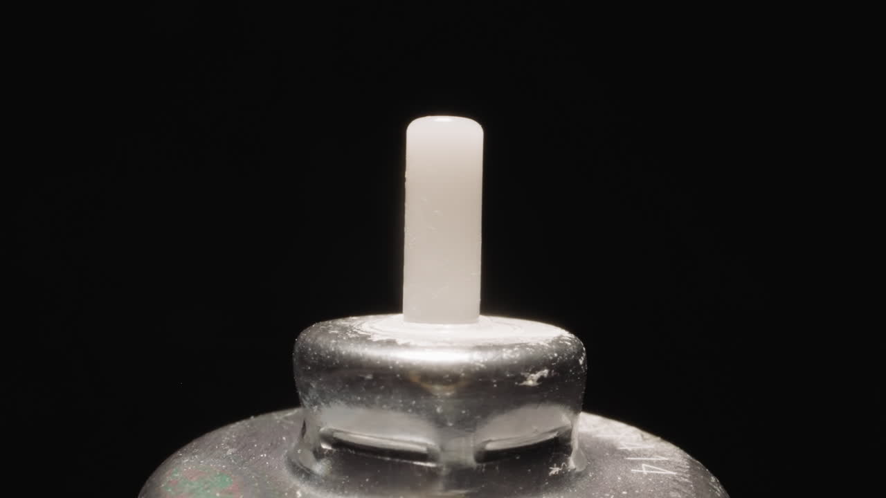 Plastic tip on metal cap of inhaler bottle shining at light