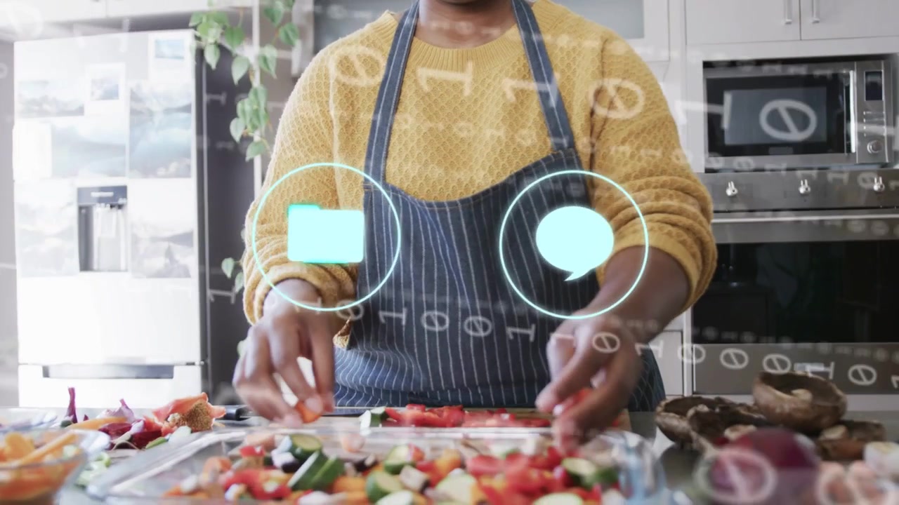 Cocinero casero organizando verduras en una bandeja en la cocina, iconos de cámara holográfica y teléfono apareciendo guiando la preparación.