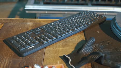 workshop table with keyboard, gloves, and metal parts