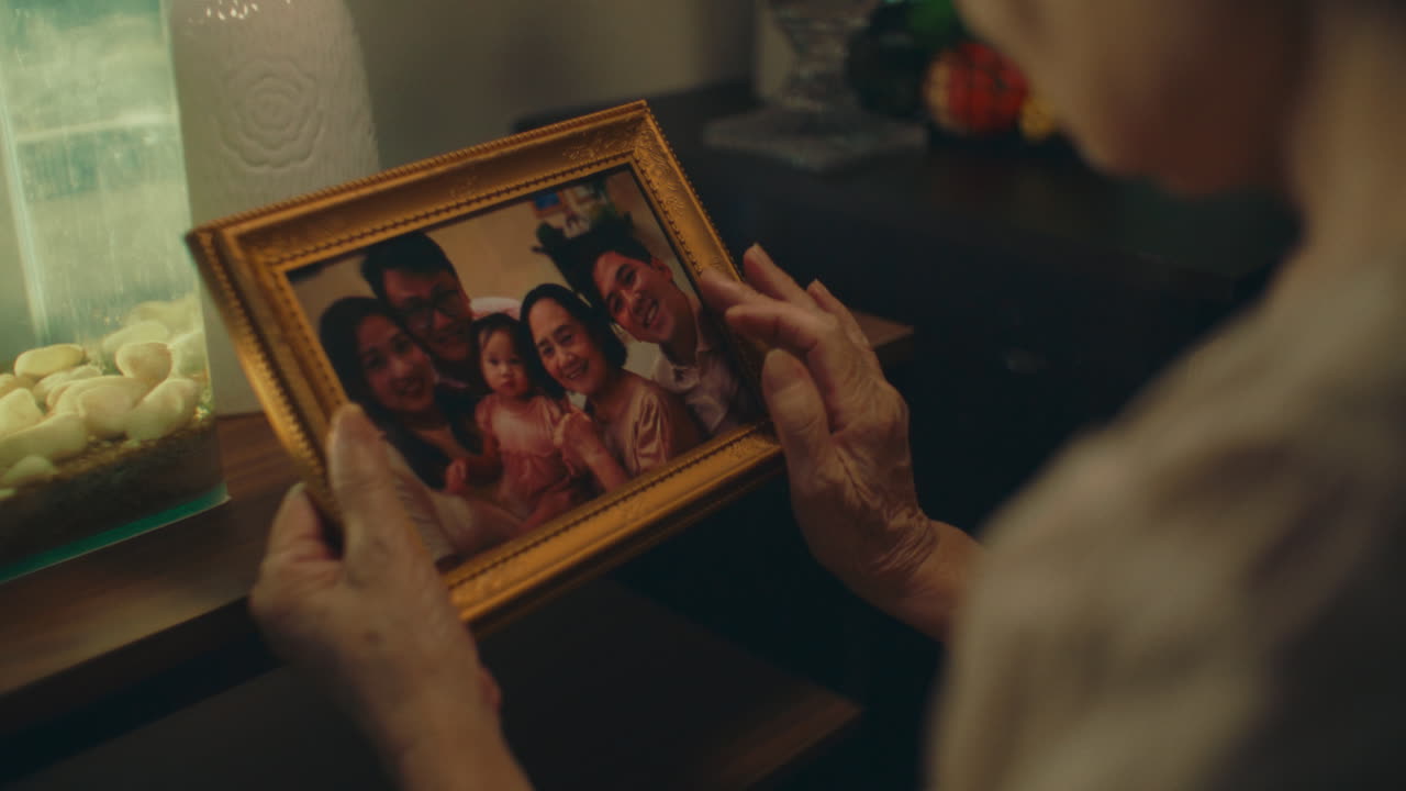 Elderly woman holding a family photo, reminiscing with nostalgia and longing