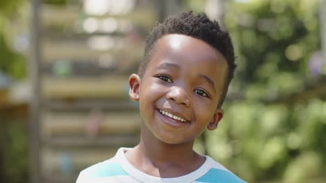 retrato de un feliz niño afroamericano sonriendo en el jardín