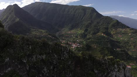 Kreisende-Drohnenaufnahme-Eines-Mannes,-Der-Vorsichtige-Schritte-Zum-Rand-Des-Steilen-Grats-Auf-Madeira-Hinaufgeht