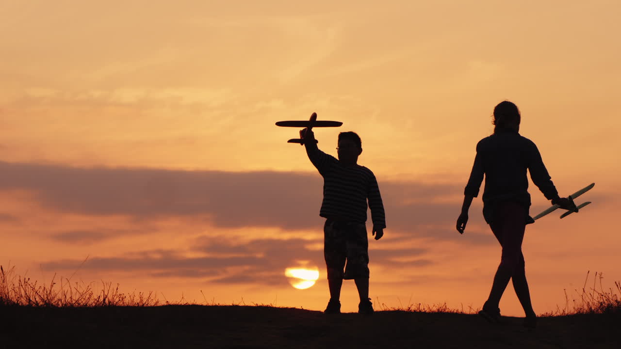 siluetas de una niña y un niño jugando juntos con aviones al atardecer un niño feliz y despreocupado