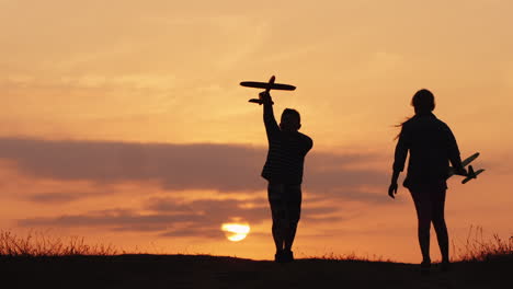 siluetas de una niña y un niño jugando juntos con aviones al atardecer un niño feliz y despreocupado