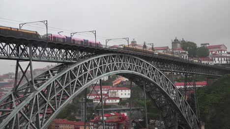 a train crossing the dom luís i bridge in porto, portugal on a cloudy day