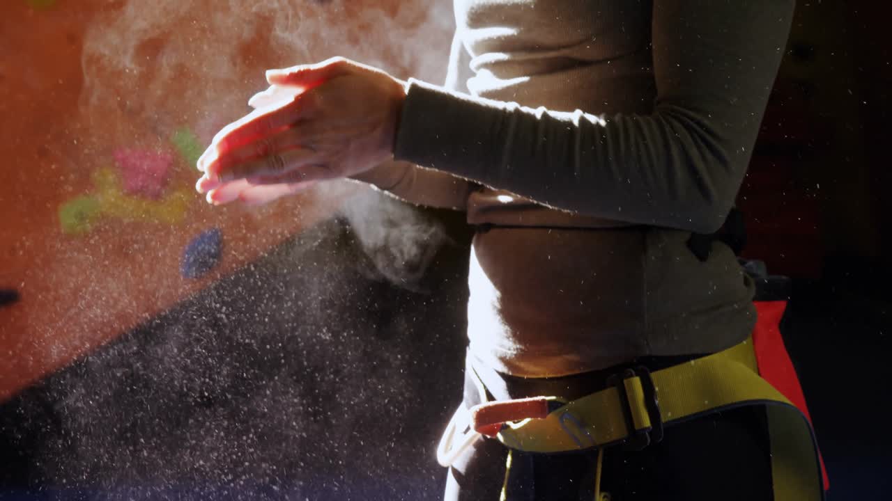 mujer quitando el polvo de tiza de sus manos en el gimnasio de bouldering 4k