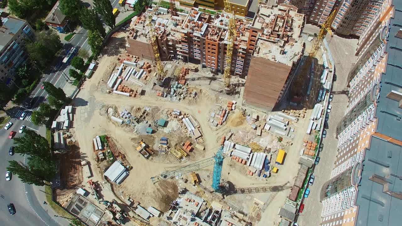 Building of new architecture near the road in the city. View from above on a construction site of a modern district in the downtown. Aerial view.