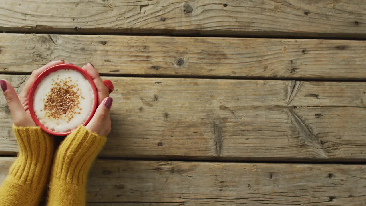 video de las manos de una mujer caucásica sosteniendo una taza con café en una superficie de madera