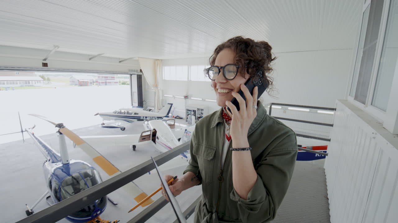 Female Aviation Safety Inspector Having Phone Conversation in Hangar