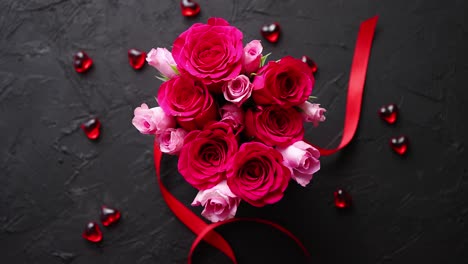 pink roses bouquet packed in red box and placed on black stone background