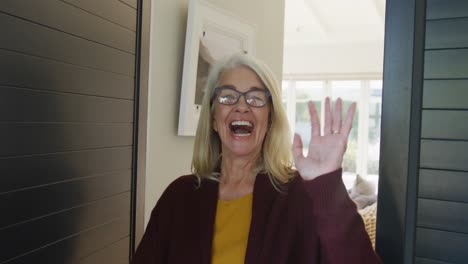 Video-of-happy-caucasian-senior-woman-opening-door-and-welcoming-someone