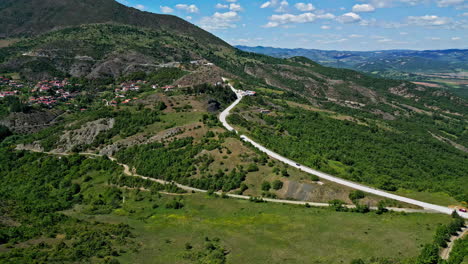 aerial drone shot flying over a town nestled along the hill and mountain slope in greece on a sunny day