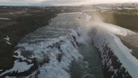 mist from gullfoss falls waterfall in iceland during beautiful sunset, aerial