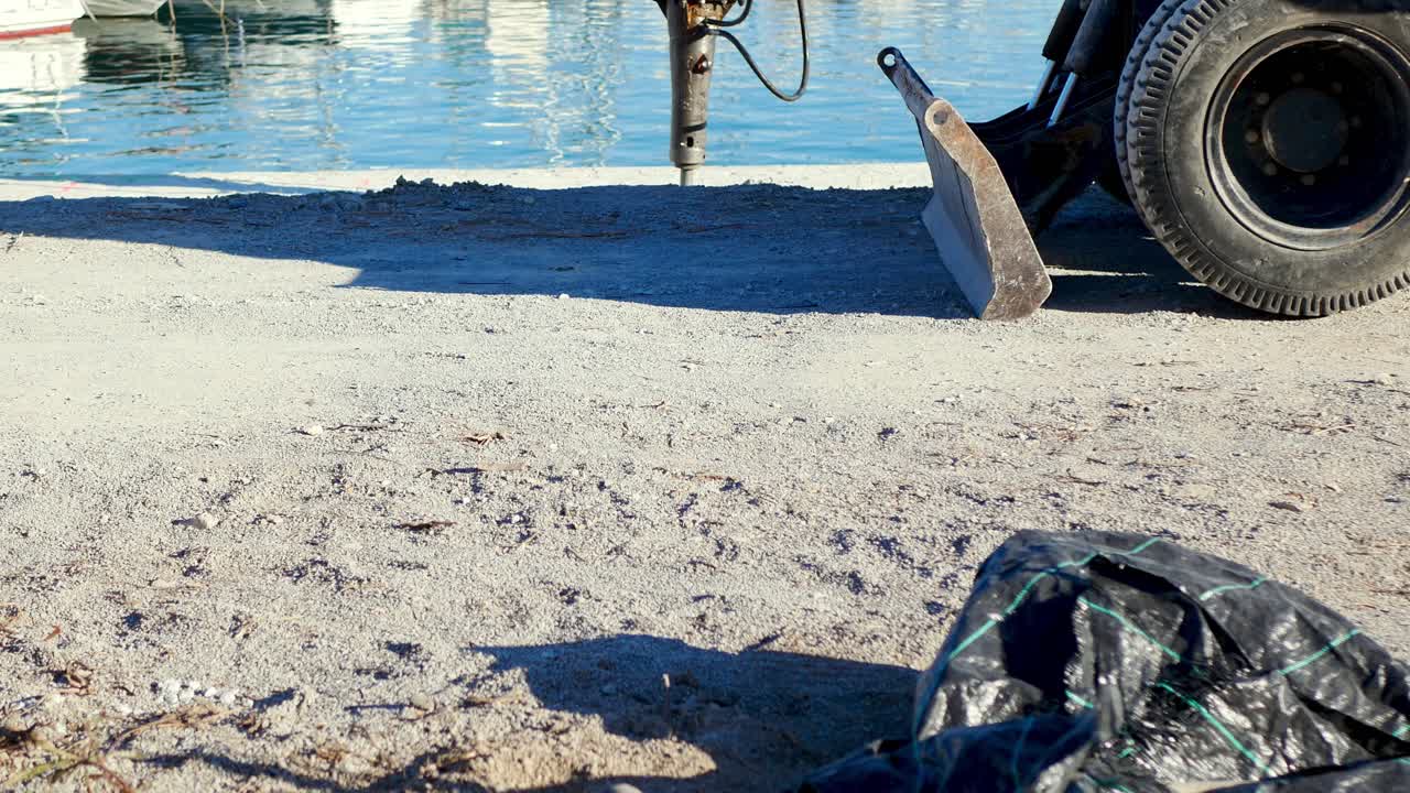 excavadora con taladro neumático rompiendo y perforando hormigón junto a un puerto