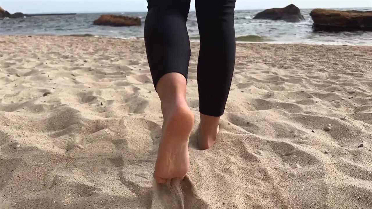 Donna che cammina a piedi nudi su una spiaggia sabbiosa