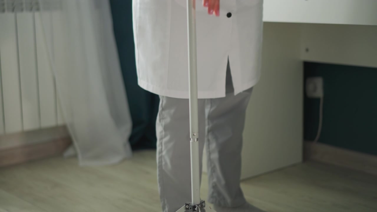 Allestimento infermieristico domiciliare. Regolazione del supporto per flebo a casa. Professionista medico prepara l'infusione al capezzale a casa. L'infermiera sistema l'attrezzatura per flebo a casa con attenzione ai dettagli.