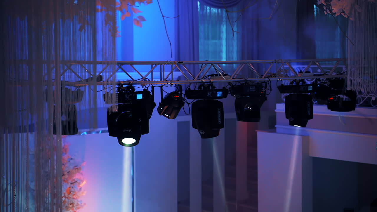 Blue background with colorful spotlights in the night club. Flashing rays with different colors glowing from projectors. Close-up.