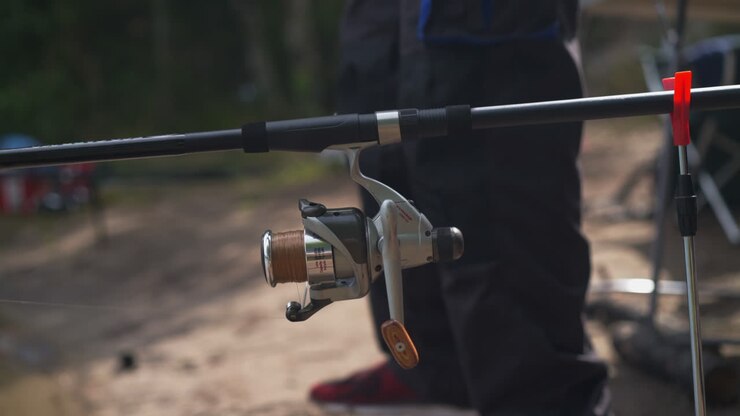 Pemancing menyiapkan dan memasang joran pancing di tepi sungai