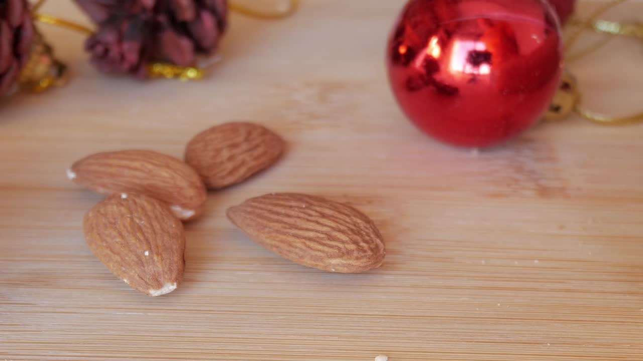 Primo piano di uovo e mandorle su una superficie di legno con pigne sullo sfondo, a simboleggiare la preparazione del Pan de Cádiz, dolce natalizio