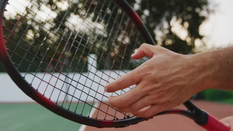 tennis player adjusting racket rope