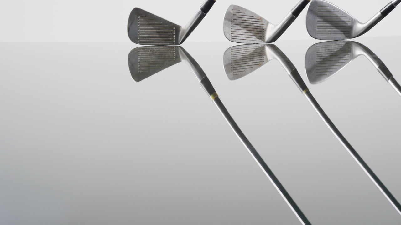 Close-up van golfclubs op witte achtergrond, met ruimte voor tekst, in slow motion.