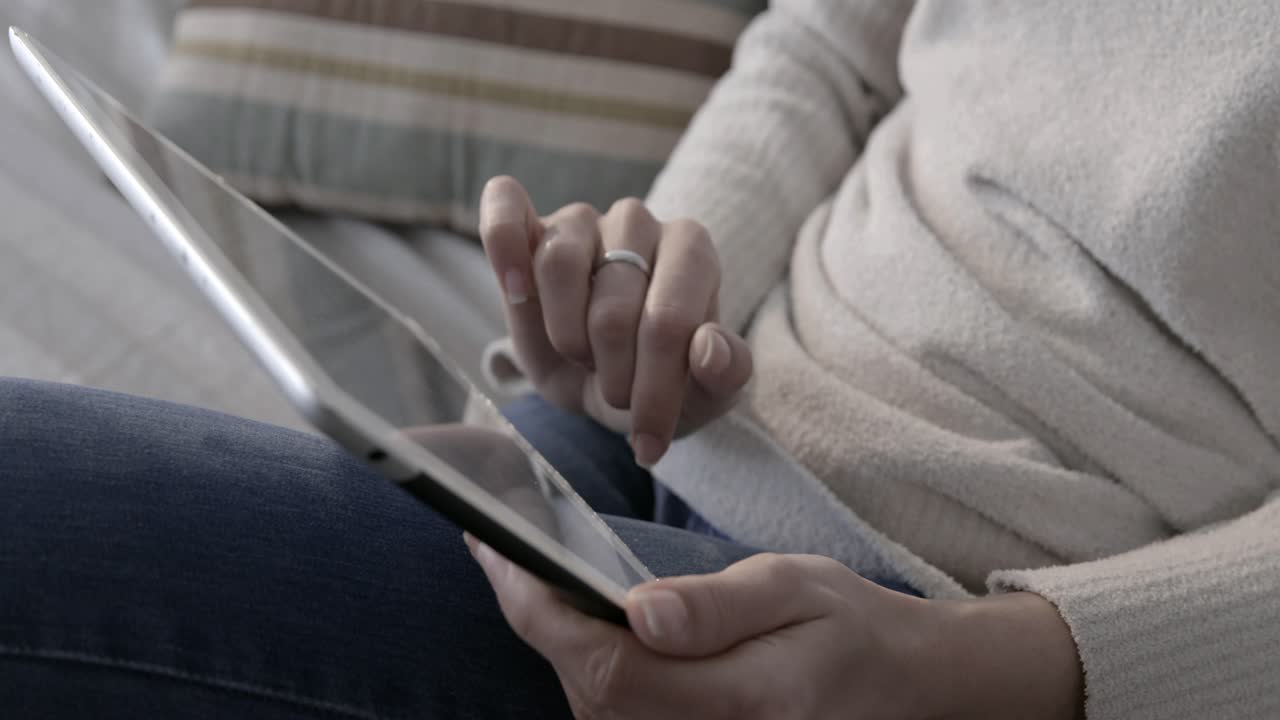 Close-up of Hands Using a Digital Tablet for Browsing